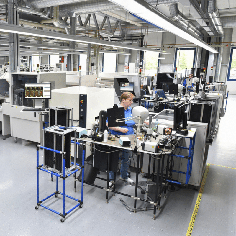 Vue d’un atelier de production électronique avec lignes CMS automatisées et opérateurs travaillant sur l’assemblage et le contrôle des cartes électroniques